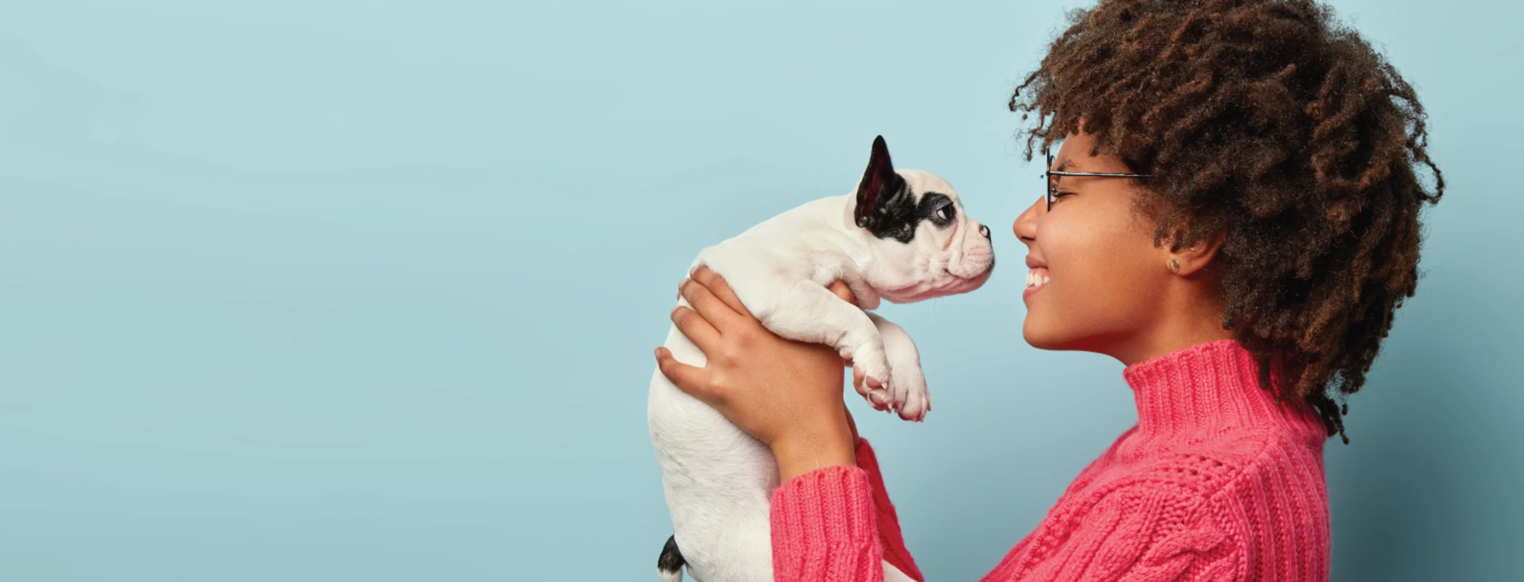 Woman holding dog on light blue background